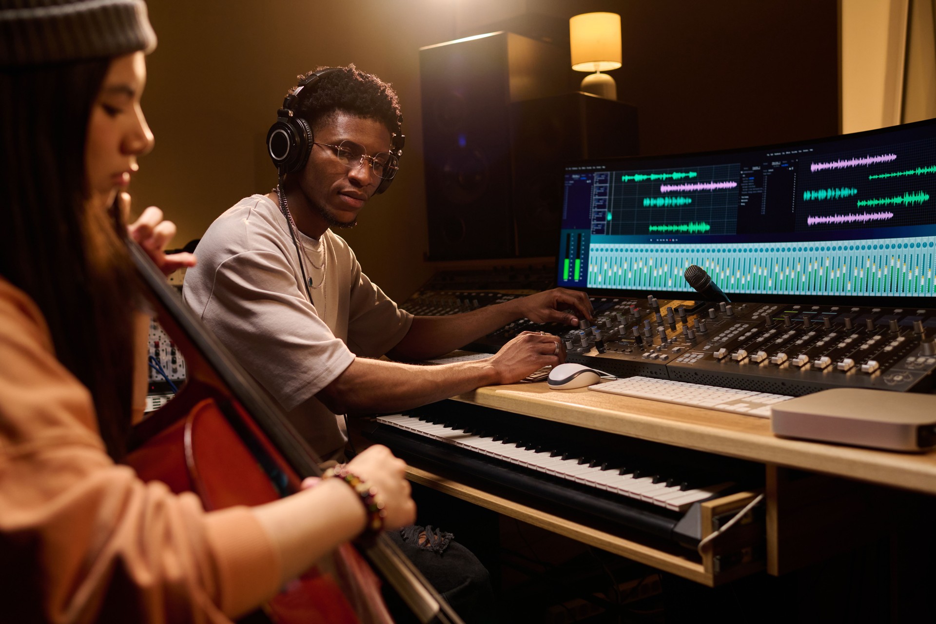 Young Black Man Producing Music with Latin Girl Playing Cello in Studio